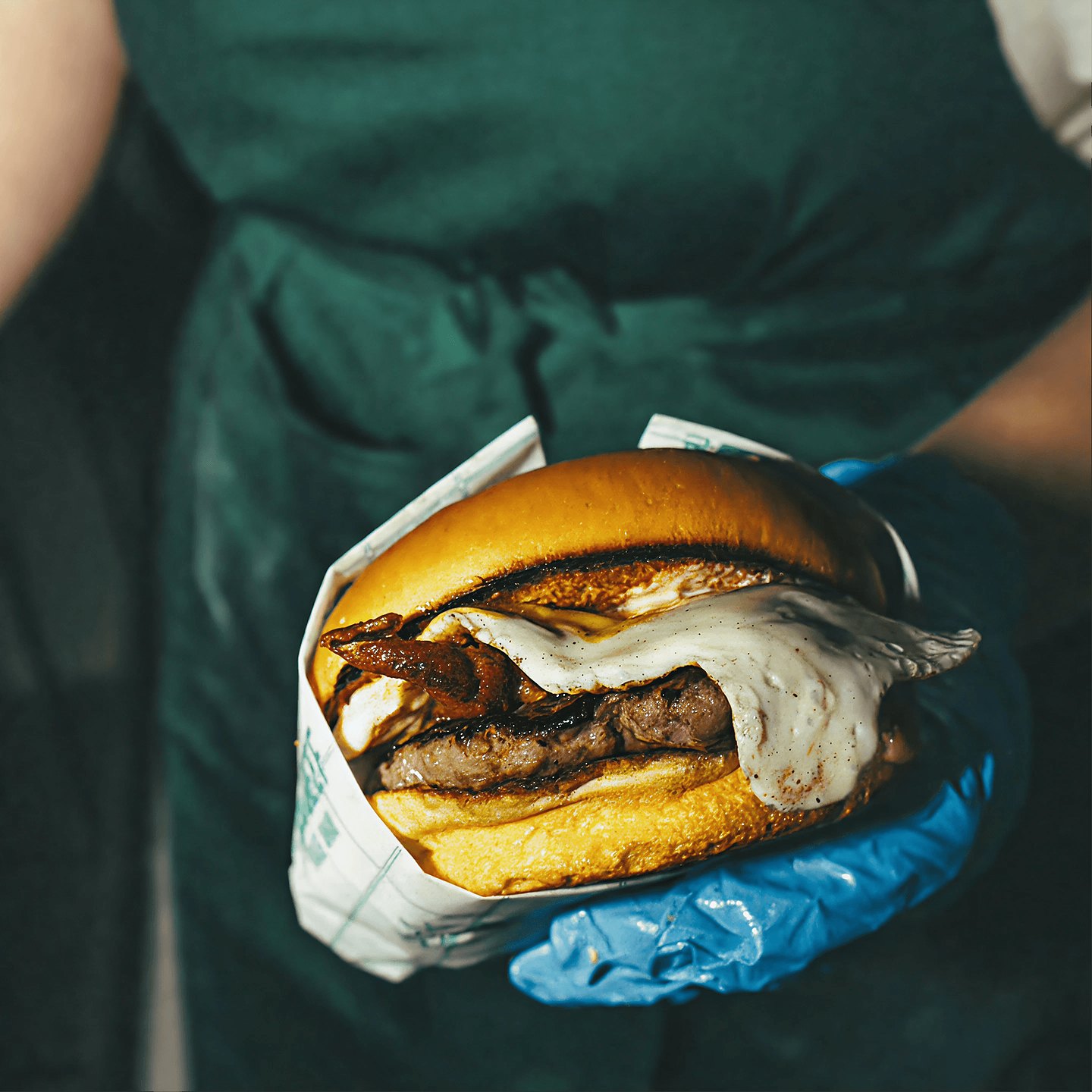 A Bulubeef burger wrapped in branded paper, handed over the counter